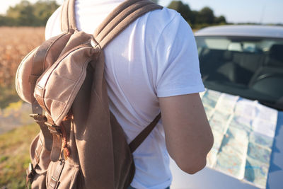 Midsection of man with map against car