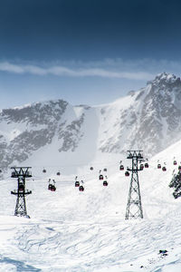 Overhead cable cars at snowcapped mountain against sky