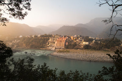 Scenic view of townscape by river against sky