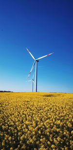 Wind turbines on field against clear sky