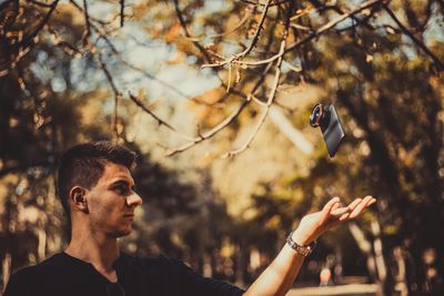 Handsome young man catching mobile phone on footpath during sunny day