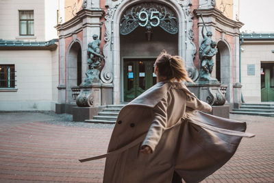 Rear view of woman walking on street against buildings