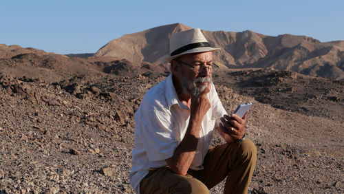 Senior man using mobile phone in the desert 