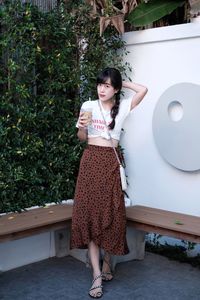 Portrait of young woman standing against trees