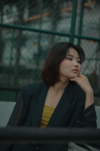 Young woman looking away while sitting outdoors