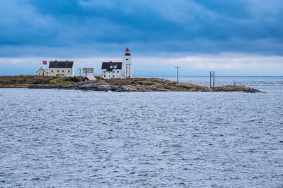 Lighthouse by sea against sky