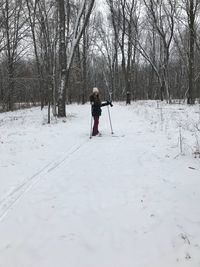 Full length teenage girl skiing on snow covered field