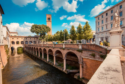 Arch bridge over river against buildings