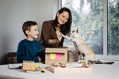 Happy family mom and kid putting bone in pet subscription box for dogs. chihuahua dog and