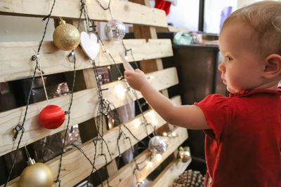 Cute baby girl looking at christmas ornaments on wooden planks