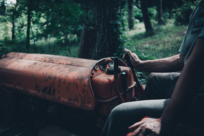 Midsection of man driving tractor in forest