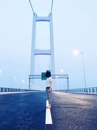 Rear view of woman standing on road against sky