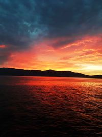 Scenic view of sea against dramatic sky during sunset