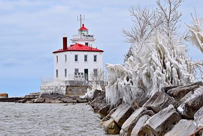 Low angle view of lighthouse by sea against sky