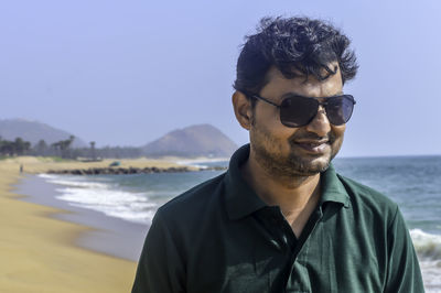 Man wearing sunglasses at beach against clear blue sky