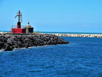 Lighthouse by sea against sky