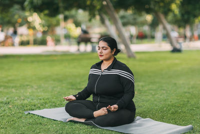 A young indian woman meditates with her eyes closed in the open air.
