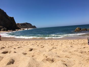 Scenic view of beach against clear blue sky