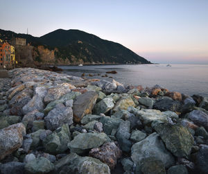 Rocks on beach against sky during sunset