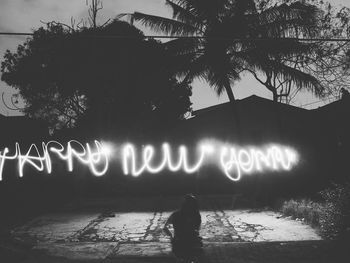 Silhouette man with illuminated text on tree at night