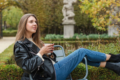 A beautiful woman is drinking hot tea and relaxing in a beautiful autumn park somewhere in europe.