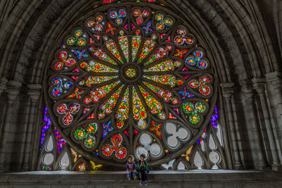 Siblings sitting against stained glass