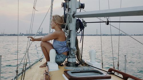 Young woman in boat sailing on sea against sky