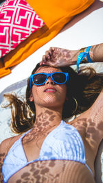 Portrait of young woman wearing sunglasses while lying outdoors