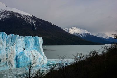 Scenic view of frozen lake by mountains against sky