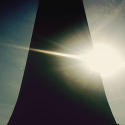 Low angle view of sun shining through clouds