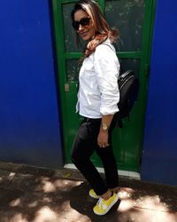 Full length of young woman standing against wall