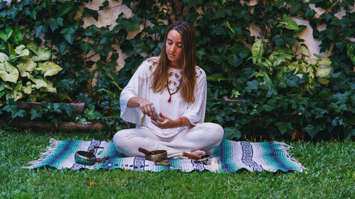 Full length of young woman making herbal medicine while sitting outdoors