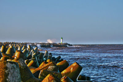 Lighthouse by sea against clear sky