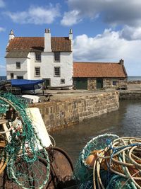 View of fishing net by buildings against cloudy sky