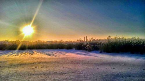 Scenic view of snow covered landscape against sky at sunset