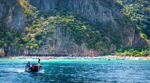 People in boat on sea against mountain