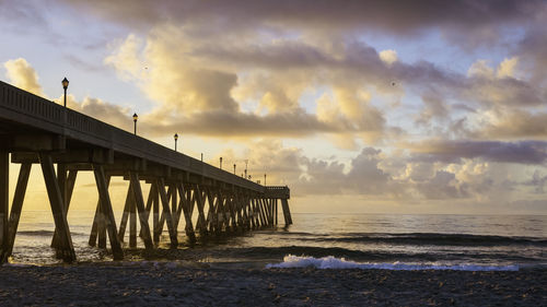 Pier over sea against sky during sunset