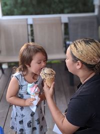 Mother and girl holding camera while standing outdoors