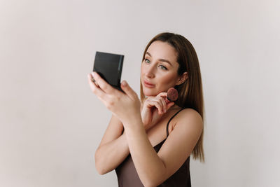 A beautiful natural woman makeup artist preens herself with makeup on a white isolated background