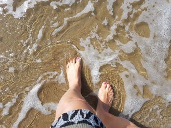 Low section of woman standing at beach