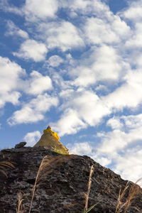 Low angle view of rocks against cloudy sky