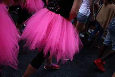 Low section of people in pink skirt walking on street