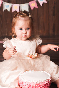 Cute baby girl with cake sitting on floor