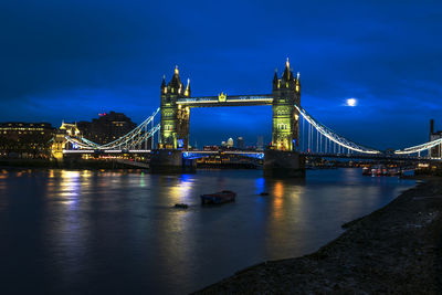 Illuminated bridge over river at night