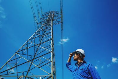 Low angle view of electricity pylon against blue sky