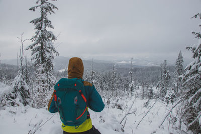 Rear view of man standing on snow covered landscape