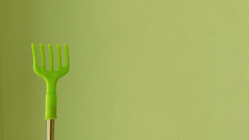 Close-up of green fork over white background