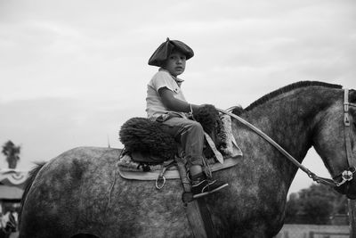 Portrait of cute south american boy riding horse