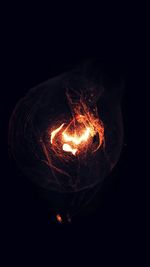 Close-up of illuminated light bulb against black background