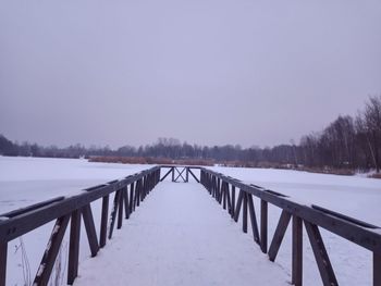 Snow covered railing against sky